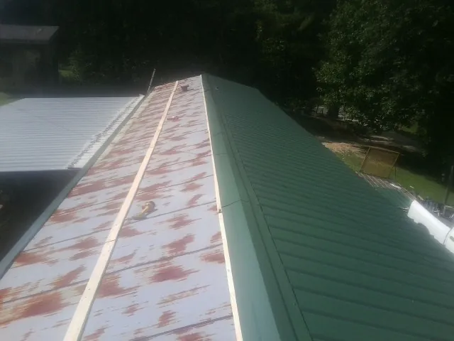 Old rusted panels beside newly installed green metal roofing — Wind Damage Roof Repair by Roofing Brothers in Gallatin Gateway