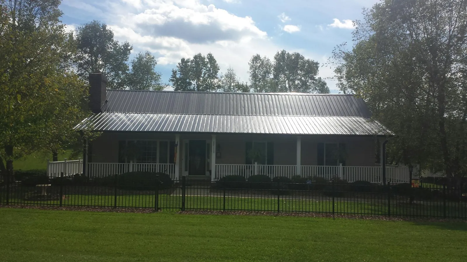 Gray metal roof on a brick ranch with a full width front porch — Gutter Guard Installation work by our crew in Gallatin Gateway