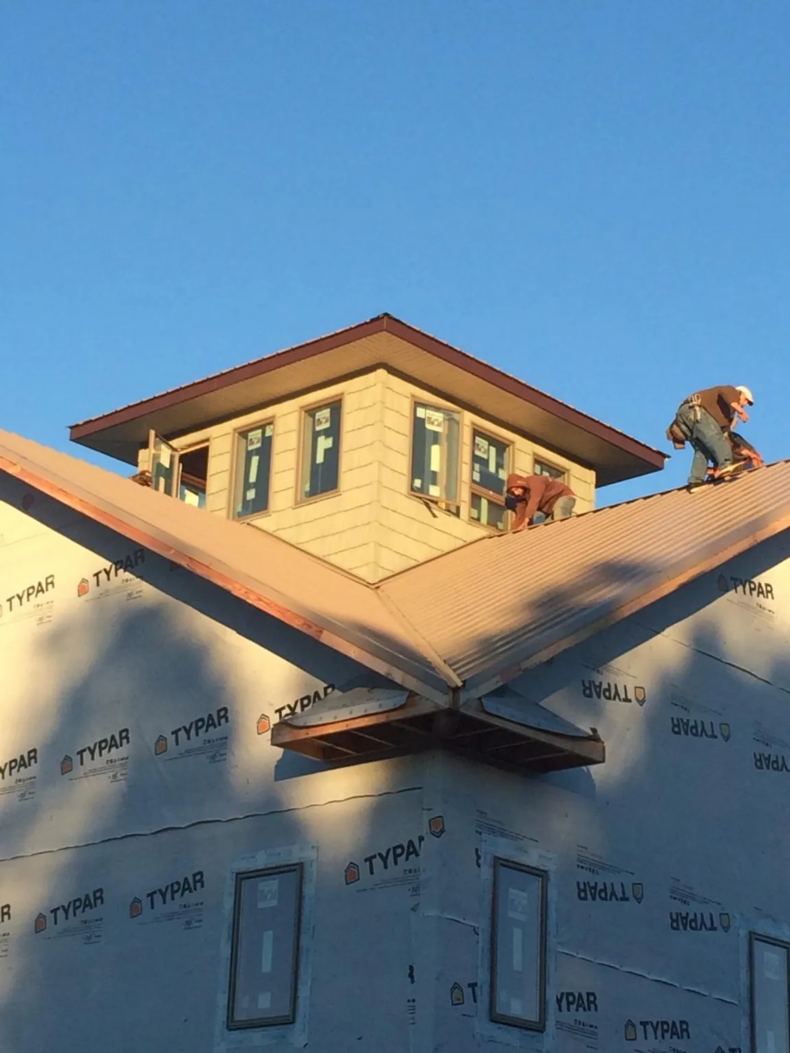 Roofers working around a rooftop cupola on a new metal roof at sunset — Roof Waterproofing in Gallatin Gateway by Roofing Brothers